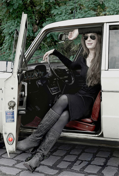 Carolin Vogt Schauspielerin - sitzt im Oldtimer outdoor schwarzes Kleid lange Haare Pilotenbrille Graue Stiefel - 2011 Foto Peter Koehn