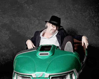 Leander Haussmann Regisseur - sitzt im grünem Autoscooter mit Sakko und Hut lässig Promifoto - 2014 Foto Peter Koehn
