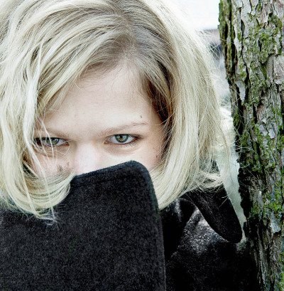 Marie Grust Schauspielerin - steht an einem Baum und hält den Mund mit dem Mantelkragen verborgen - 2010 Foto Peter Koehn