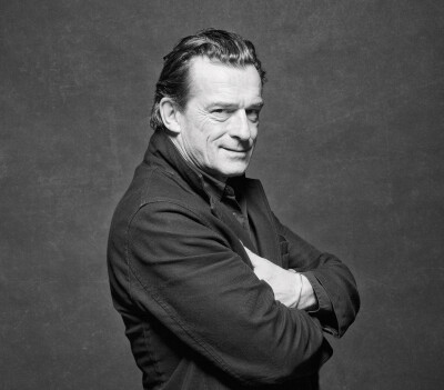 Thomas Sarbacher Schauspieler - steht im Fotostudio Häne verschrenkt lacht schwarzer Mantel schwarz weiß Foto - 2012 Foto Peter Koehn