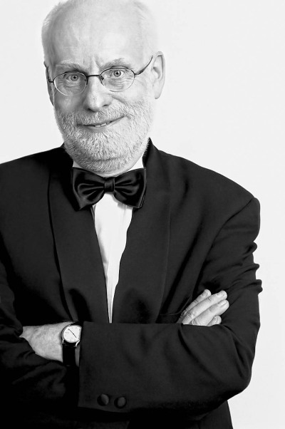 Ton Koopmann Musiker - steht im schwarzen Anzug mit Fliege im Studio und lacht ist Buxtehude Preisträger 2012 - 2015 Foto Peter Koehn